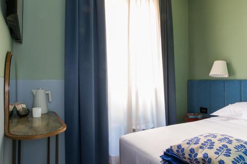 a bedroom with a bed and a window with blue curtains at Condominio Monti Boutique Hotel in Rome