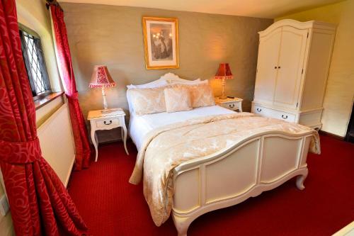a bedroom with a large white bed and two tables at The Roundabout Hotel in Pulborough