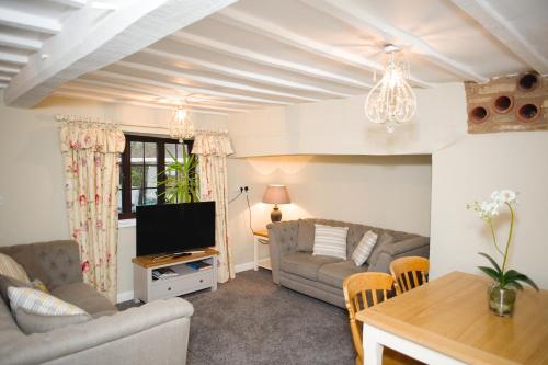 a living room with a couch and a tv at Rutland Water Courtyard Rooms in Oakham
