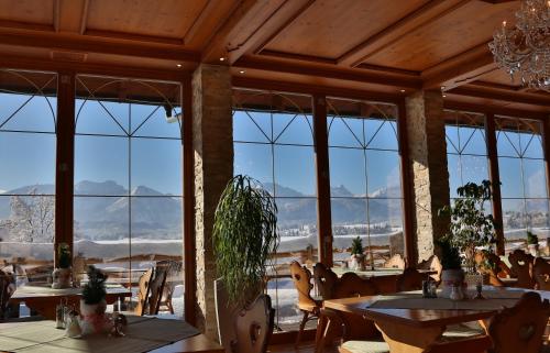 a restaurant with tables and chairs and large windows at Seehotel Hartung & Ferienappartements in Füssen