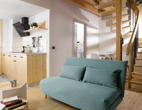 un salon avec un canapé bleu et une cuisine dans l'établissement Hôtel Au Petit Pont, à La Wantzenau