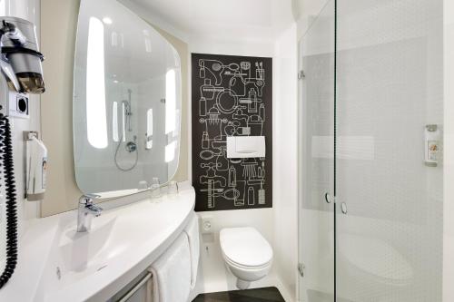 a white toilet sitting next to a shower in a bathroom at ibis Glasgow City Centre – Sauchiehall St in Glasgow
