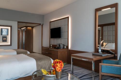 a hotel room with a bed and a desk with a television at Landmark Amman Hotel & Conference Center in Amman