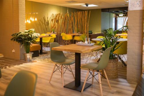 a table and chairs in a restaurant with yellow chairs at Bed & Breakfast Van Marion in Oostvoorne