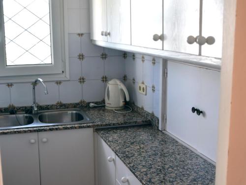 eine Küche mit weißen Schränken und einem Waschbecken in der Unterkunft Balu in Lloret de Mar