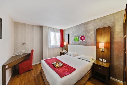 a hotel room with a large bed and a desk at HOTEL RESTAURANT PARIS PACIFIC PARIS-VILLEJUIF- PRES DU METRO L'HAY LES ROSES LIGNE 14 - Direct PARIS-AEROPORT ORLY ET INSTITUT GUSTAVE ROUSSI in Villejuif