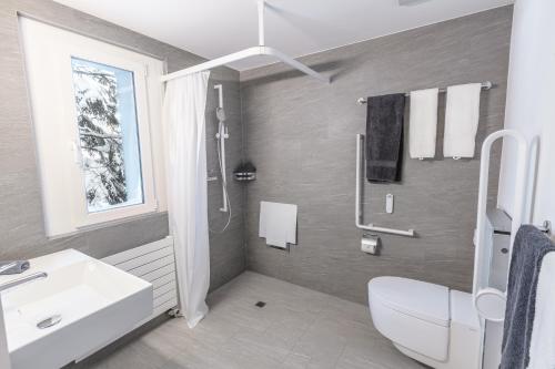 La salle de bains est pourvue d'un lavabo blanc et de toilettes. dans l'établissement Hotel Seebüel, à Davos