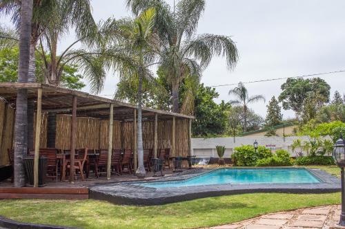 a house with a swimming pool and palm trees at Big Ben Lodge in Polokwane