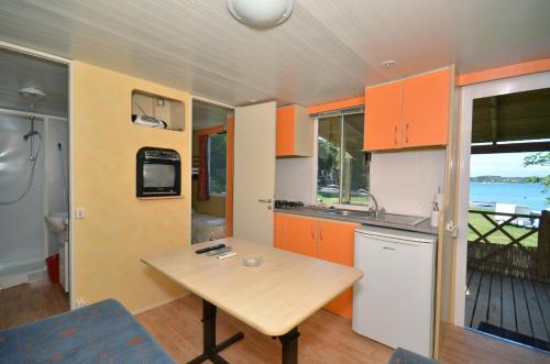 cocina con armarios naranjas y mesa de madera en Arena Tasalera Mobile Homes, en Premantura