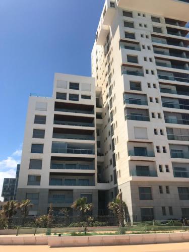 ein hohes weißes Gebäude mit Palmen davor in der Unterkunft Appartement Casa-marina au 10ème étage in Casablanca