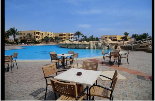 a group of tables and chairs next to a swimming pool at Blend Elphistone Resort Marsa Alam in Abu Dabab