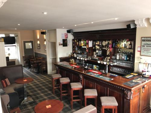 un bar dans un pub avec un bouquet de tabourets de bar dans l'établissement Aberdour Hotel, Stables Rooms & Beer Garden, à Aberdour