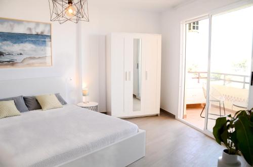 Habitación blanca con cama y balcón. en Duquesa de España, en Torremolinos