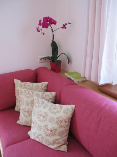 a pink couch with pillows and a plant on a window at Gästehaus Bergstüberl in Reit im Winkl