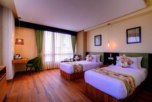 a hotel room with two beds and a desk at Udaan Clover Hotel Banquet & Spa in Siliguri