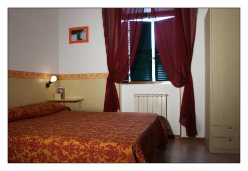 a bedroom with a bed and a window with red curtains at Due Torri in San Severino Marche