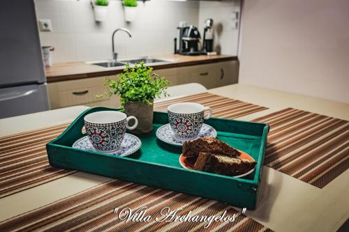a tray with a piece of cake and two cups of coffee at Villa Archangelos in Archángelos
