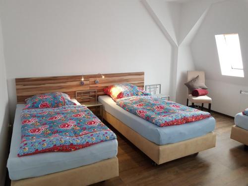 ライヒェンバッハ・イム・フォークトラントにあるApartments Vogtlandblickのベッドルーム1室(ベッド2台、木製ヘッドボード付)