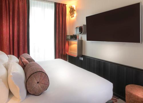 a hotel room with a bed and a flat screen tv at Hotel Du Cadran in Paris