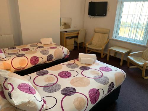 a room with two beds and a table and chairs at Austins Guest House in Cardiff