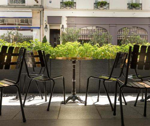 a table and chairs on a patio with plants at Hotel Du Cadran in Paris
