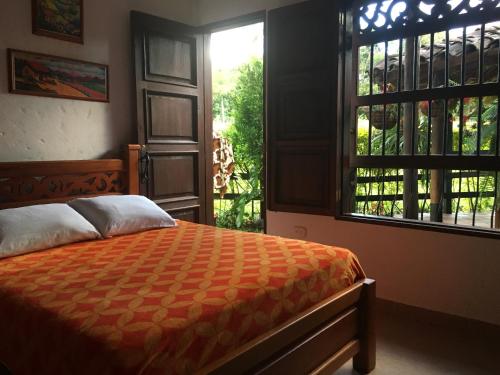 a bedroom with a bed and two windows at Casa Hotel Portón Campestre in Jardin