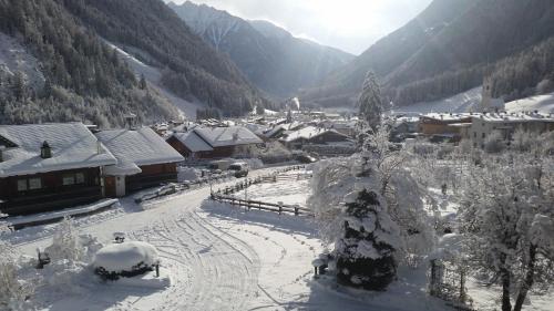 a village covered in snow with mountains in the background at Hotel Schwarzbachhof in Lutago