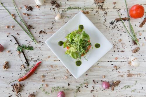 a white plate with a salad on a wooden table at Mayo Resort in Umeanyar