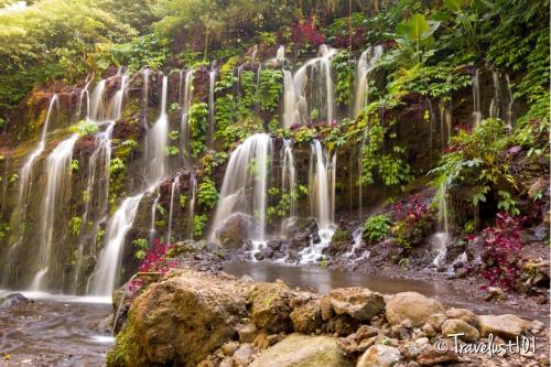 a waterfall in a garden with flowers at Mayo Resort in Umeanyar