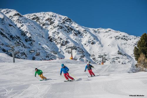 three people are skiing down a snow covered mountain at Hotel Schwarzbachhof in Lutago