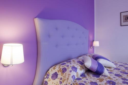 a bedroom with a bed with purple walls and two lamps at Casa Vacanza Villa Aurora in Laureana Cilento