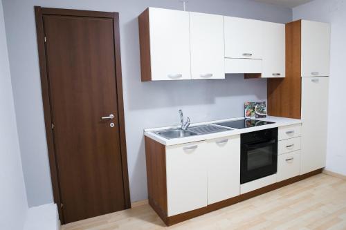 a kitchen with white cabinets and a sink and a door at Vittoria Guest House Salerno in Salerno