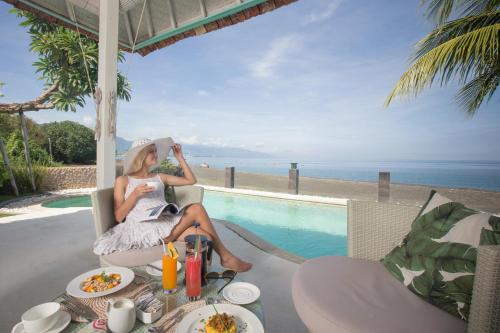 a woman sitting on a chair next to a pool at Mayo Resort in Umeanyar