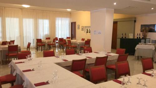 un comedor con mesas blancas y sillas rojas en Hotel Minerva, en Brindisi