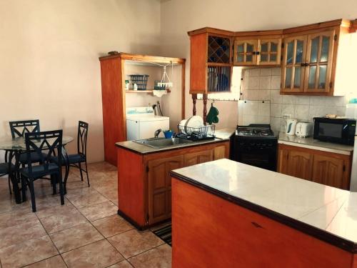 a kitchen with wooden cabinets and a table with chairs at Nicolodge Apartments in Christ Church
