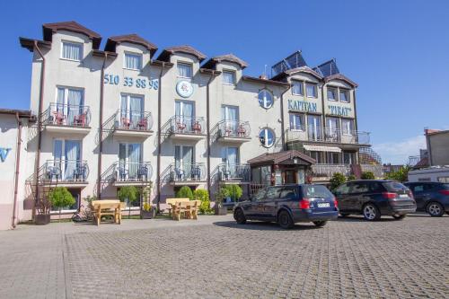 un gran edificio con coches estacionados frente a él en Kapitan Pirat, en Władysławowo