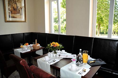 a dining room with two tables and chairs with flowers at Waldhotel Rheinbach in Rheinbach