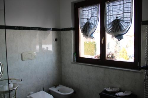 a bathroom with a toilet and a sink and two windows at Bed & Breakfast Milù in Cuneo