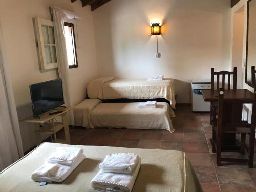 a small room with two beds and a television at HOSTERÍA SAJONIA in Villa Gesell