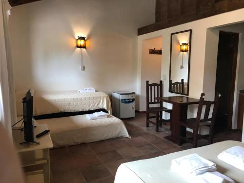 Cette chambre comprend 2 lits, une table et un miroir. dans l'établissement HOSTERÍA SAJONIA, à Villa Gesell