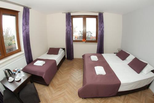 a room with two beds and a table and windows at Cztery Ściany nad Tałtami in Mikołajki