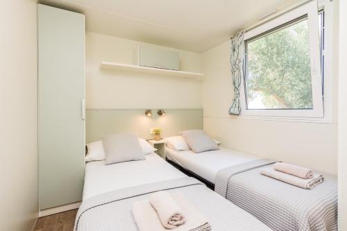 2 Betten in einem kleinen Zimmer mit Fenster in der Unterkunft Camp Port in Pakoštane