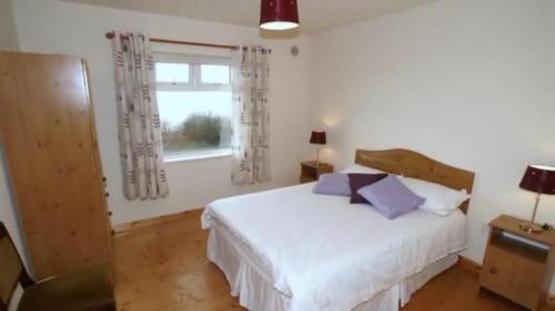 a bedroom with a white bed and a window at Three bedroom holiday home in Port