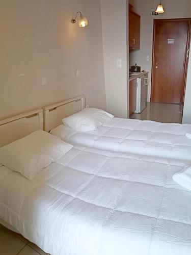 a bedroom with two white beds and a kitchen at Gorgones, sea-front, great view in Kardamili