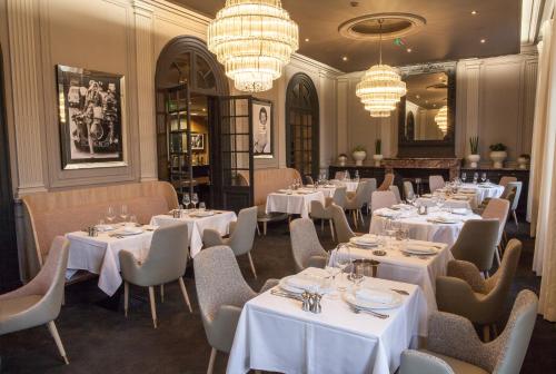 un restaurant avec des tables, des chaises et des lustres blancs dans l'établissement The Originals Boutique, La Maison Rouge, Lens Ouest (Qualys-Hotel), à Noeux-les-Mines