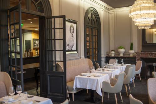 a restaurant with white tables and chairs and a chandelier at The Originals Boutique, La Maison Rouge, Lens Ouest in Noeux-les-Mines