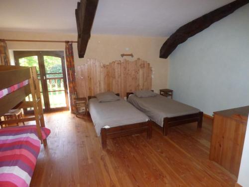 sypialnia z 2 łóżkami i drewnianą podłogą w obiekcie La Pénardière w mieście Saint-Étienne-de-Tulmont