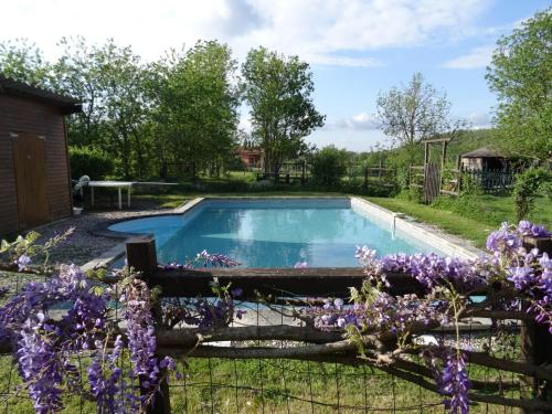 een zwembad in een tuin met paarse bloemen bij La Pénardière in Saint-Étienne-de-Tulmont