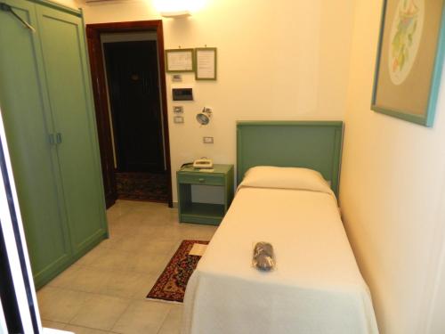a small room with a bed and a green door at Hotel Il Mulino in Capo dʼOrlando