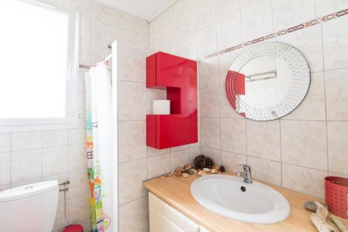 La salle de bains est pourvue d'un lavabo et d'un miroir rouge. dans l'établissement Le Studio Rouge de la Gare, à Vieux-Boucau-les-Bains